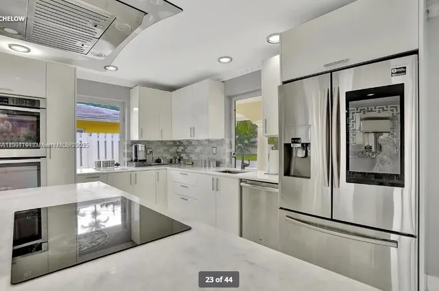 a kitchen with stainless steel appliances granite countertop a refrigerator a stove and a sink