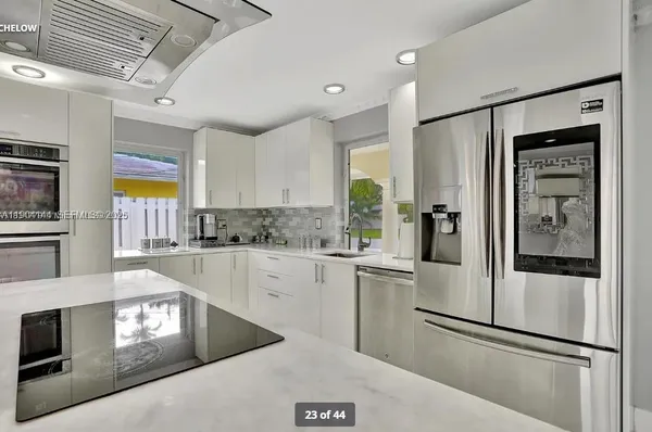 a kitchen with stainless steel appliances granite countertop a refrigerator a stove and a sink