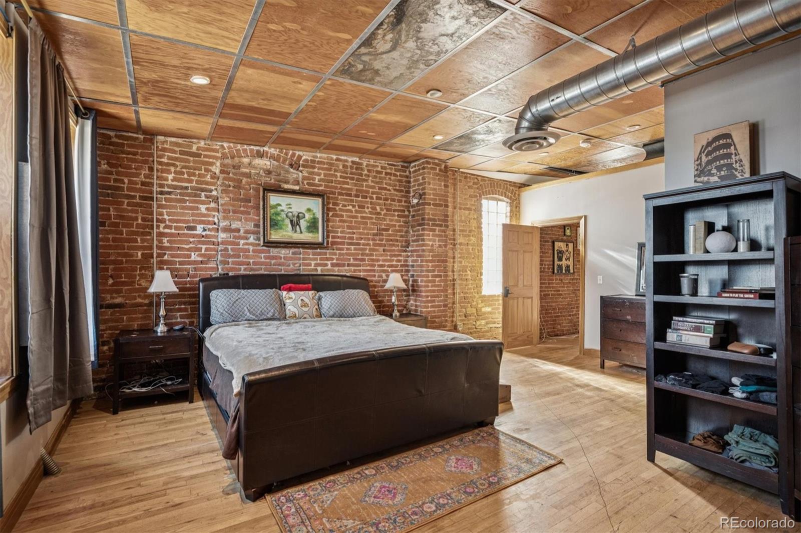 760 Santa Fe Drive, Unit 2 Denver, CO 80204 - Photo 25 of 33 a bedroom with a bed and a book shelf
