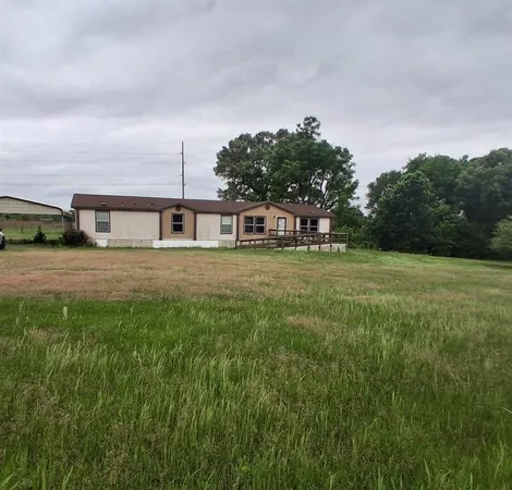 a view of a house with a big yard and large trees