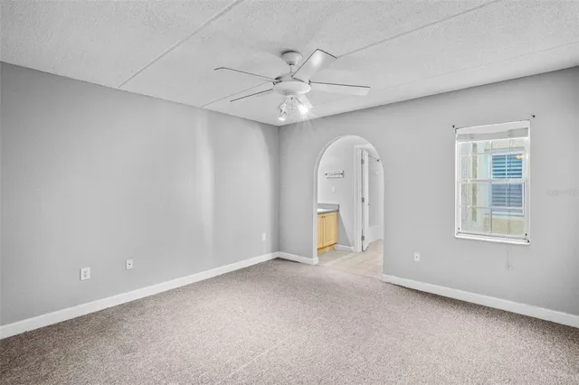 an empty room with windows and fan