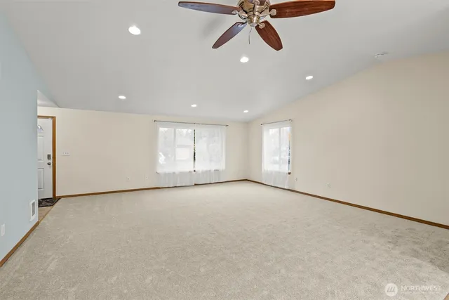 an empty room with windows and fan