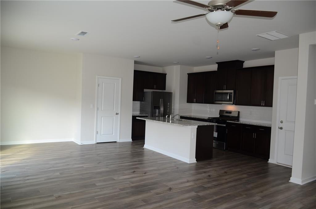 226 Wells Circle Canton, GA 30114 - Photo 5 of 27 a kitchen with stainless steel appliances kitchen island granite countertop a stove top oven a sink and dishwasher with wooden floor