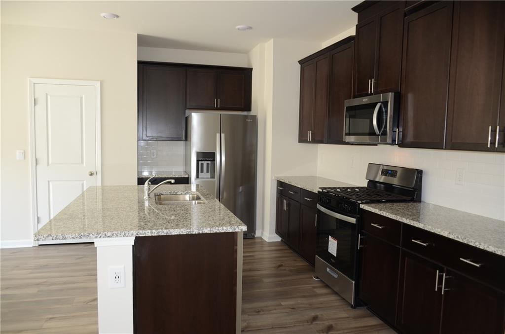 226 Wells Circle Canton, GA 30114 - Photo 6 of 27 a kitchen with kitchen island granite countertop stainless steel appliances a sink stove refrigerator and a window