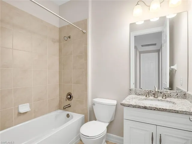 a bathroom with a granite countertop sink a toilet and shower