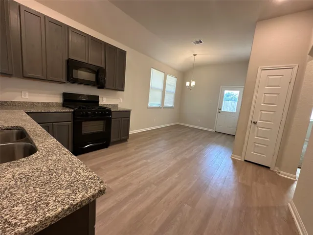 a kitchen with granite countertop wooden cabinets and black stainless steel appliances