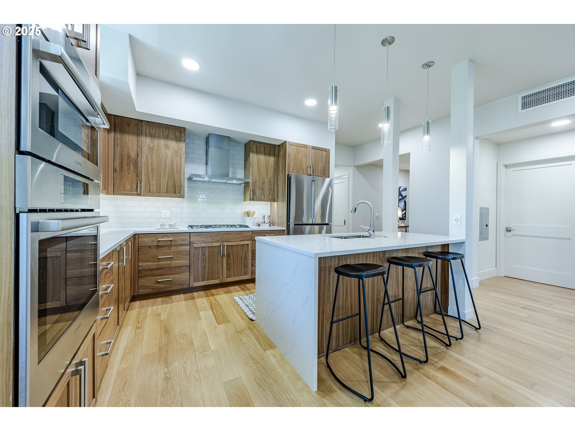 1600 Pearl Street, Unit 303 Eugene, OR 97401 - Photo 16 of 32 a kitchen with kitchen island granite countertop wooden floors and white cabinets