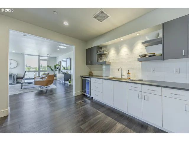 a kitchen with stainless steel appliances granite countertop a sink a stove a kitchen island with chairs and wooden floor