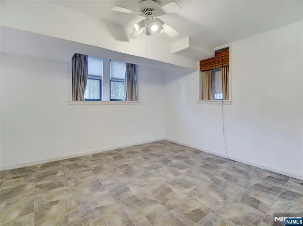 a view of an empty room with window and chandelier fan