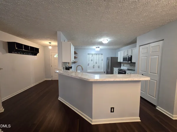 a kitchen with white cabinets sink and chairs
