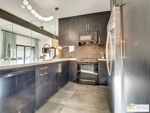 a kitchen with stainless steel appliances kitchen island granite countertop a refrigerator and a sink