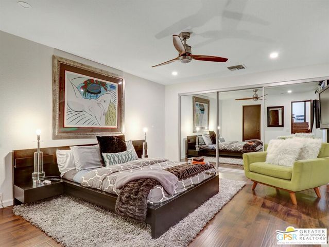 a spacious bedroom with a bed a couch and paintings on the wall