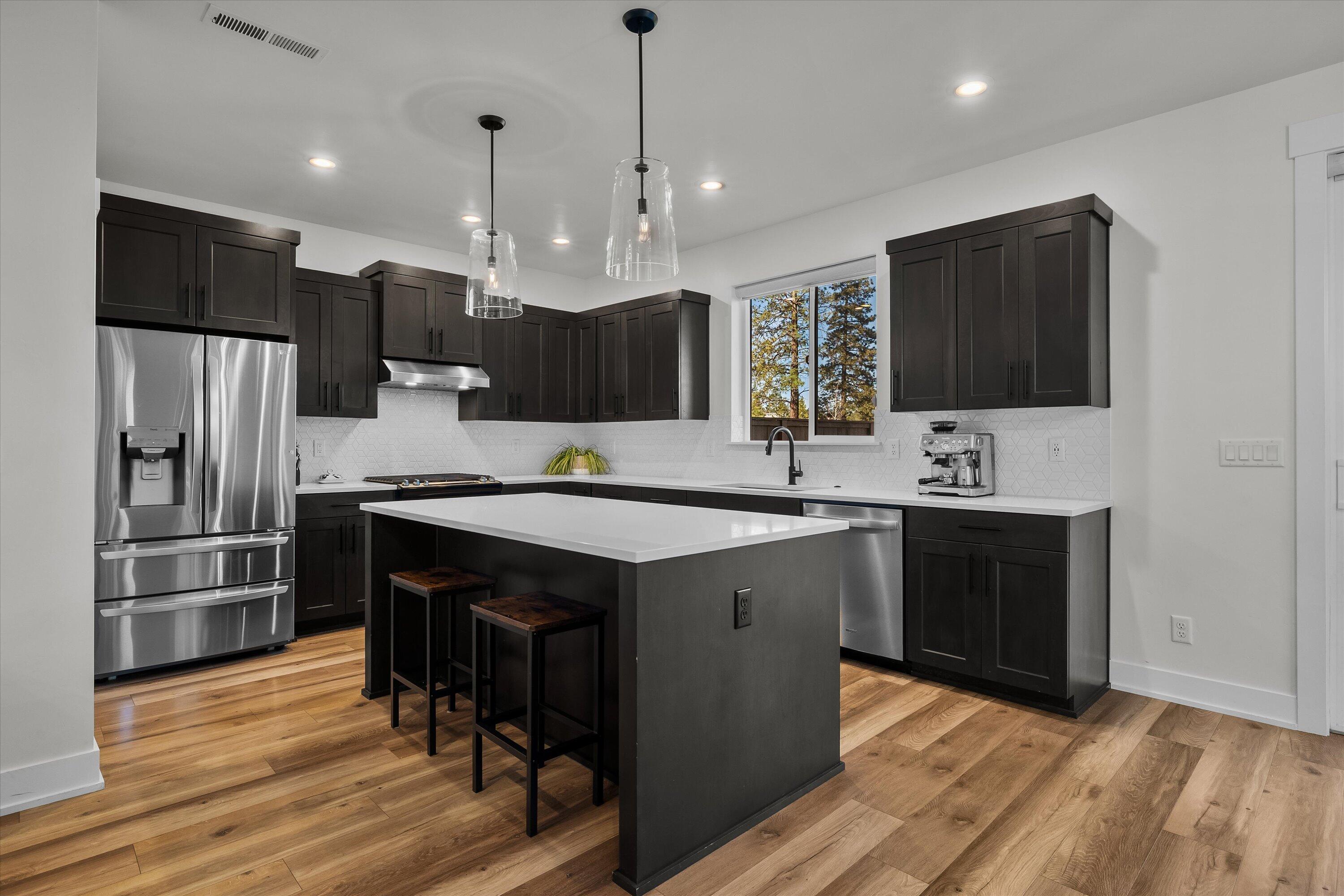 60903 Southeast Epic Place Bend, OR 97702 - Photo 12 of 48 a kitchen with kitchen island a sink stainless steel appliances and wooden floor