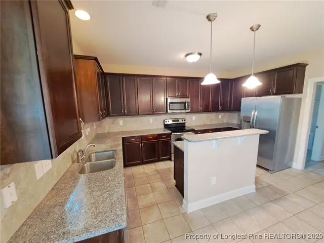 a kitchen with stainless steel appliances granite countertop a refrigerator a stove a sink and a oven