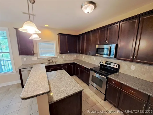 a kitchen with kitchen island granite countertop stainless steel appliances a sink stove and microwave
