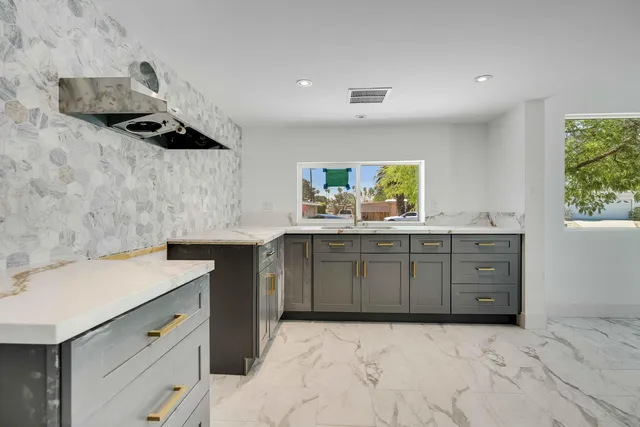 a view of an empty room with a window and kitchen view