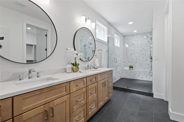 a spacious bathroom with a double vanity sink a mirror and a shower