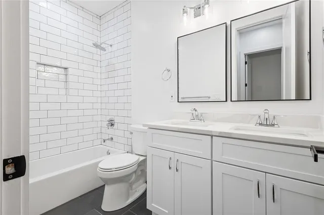 a bathroom with a toilet sink a mirror a bathtub and shower