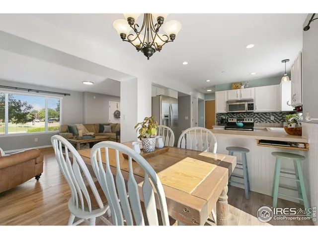 a kitchen with stainless steel appliances granite countertop a sink a stove a dining table and chairs