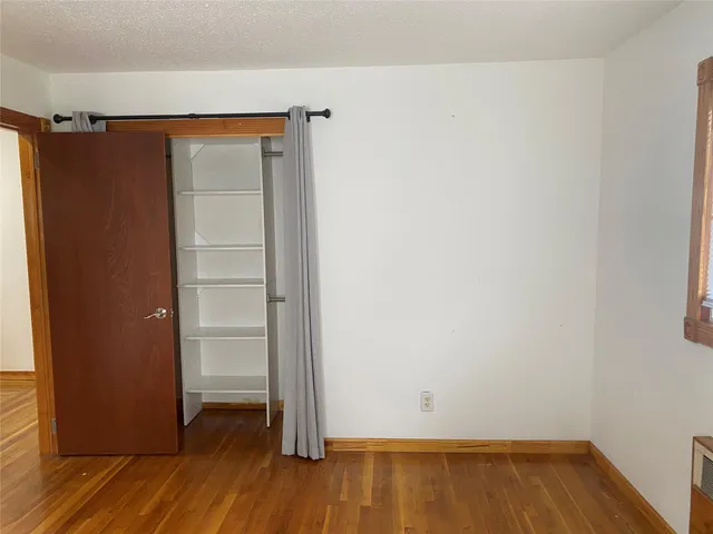an empty room with wooden floor and closet