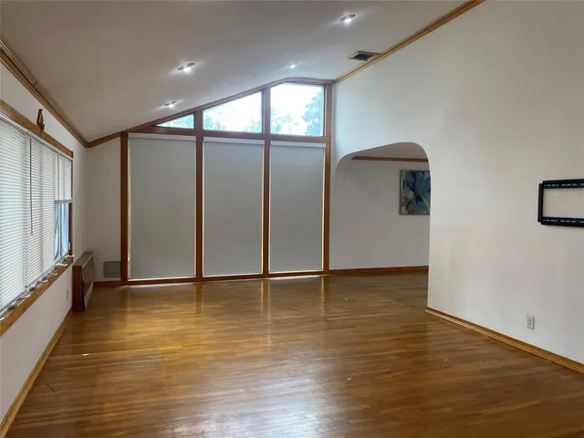 a view of an empty room with window and wooden floor