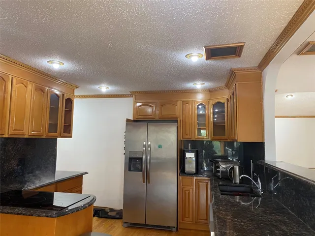 a kitchen with stainless steel appliances granite countertop a refrigerator a stove and a sink with wooden floor