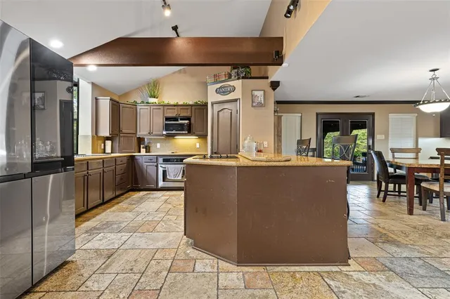 a living room with stainless steel appliances kitchen island granite countertop a table and chairs in it