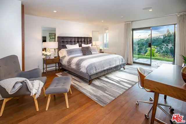 a bedroom with a bed a lamp and a large window