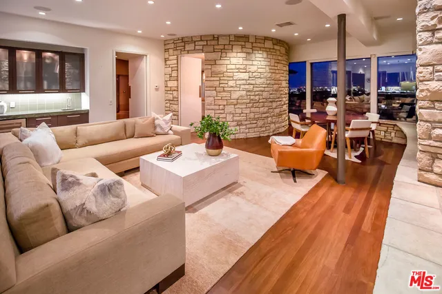 a living room with furniture kitchen view and a large window