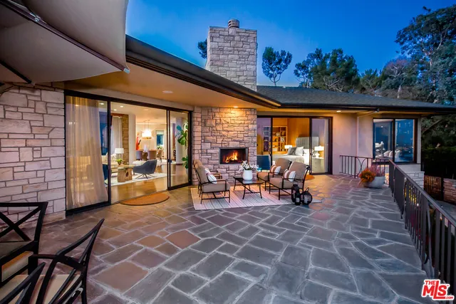a view of a patio with dining table and chairs with plants and wooden fence