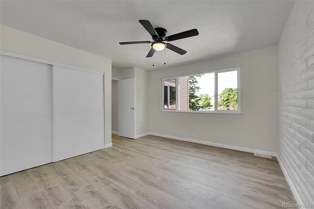 an empty room with ceiling fan and windows