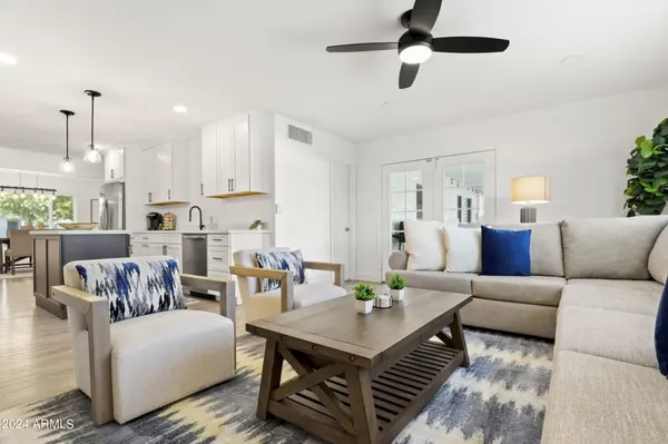a living room with furniture kitchen view and a chandelier