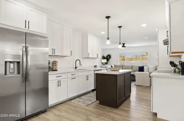 a kitchen with stainless steel appliances granite countertop a refrigerator a sink dishwasher a s stove top oven a large island with white cabinets and wooden floor