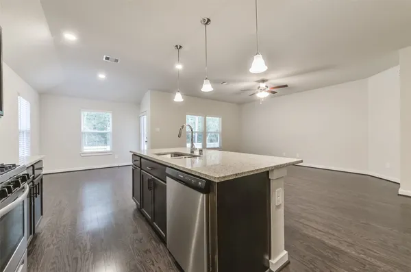 a kitchen with a stove a sink and wooden floor