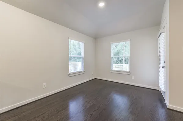 an empty room with wooden floor and windows