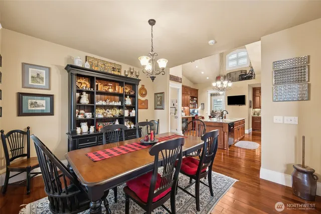 a kitchen with stainless steel appliances granite countertop a stove top oven a sink dishwasher and a dining table with wooden floor