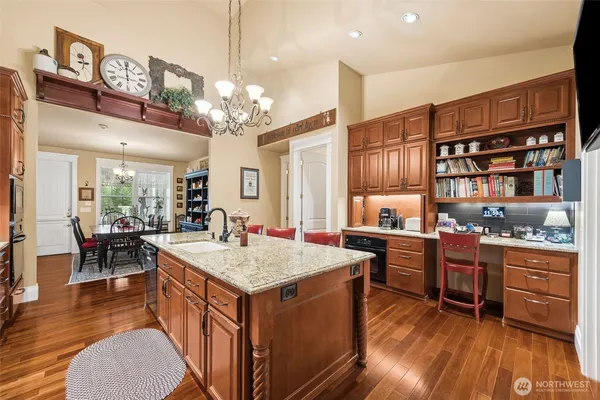 a kitchen with stainless steel appliances granite countertop a stove top oven a sink dishwasher and a dining table with wooden floor