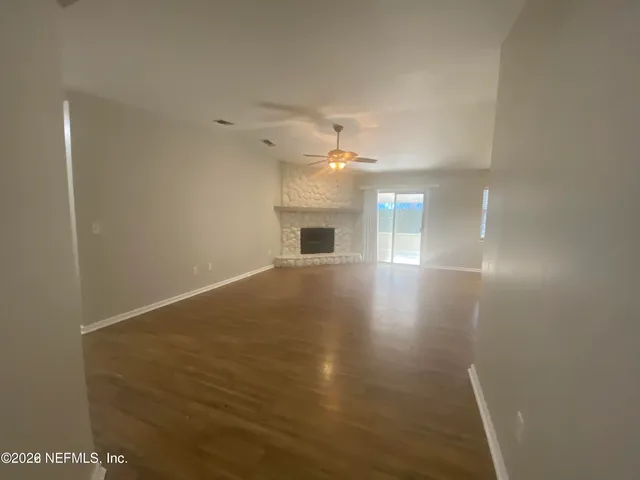 a view of an empty room with chandelier fan and fire place