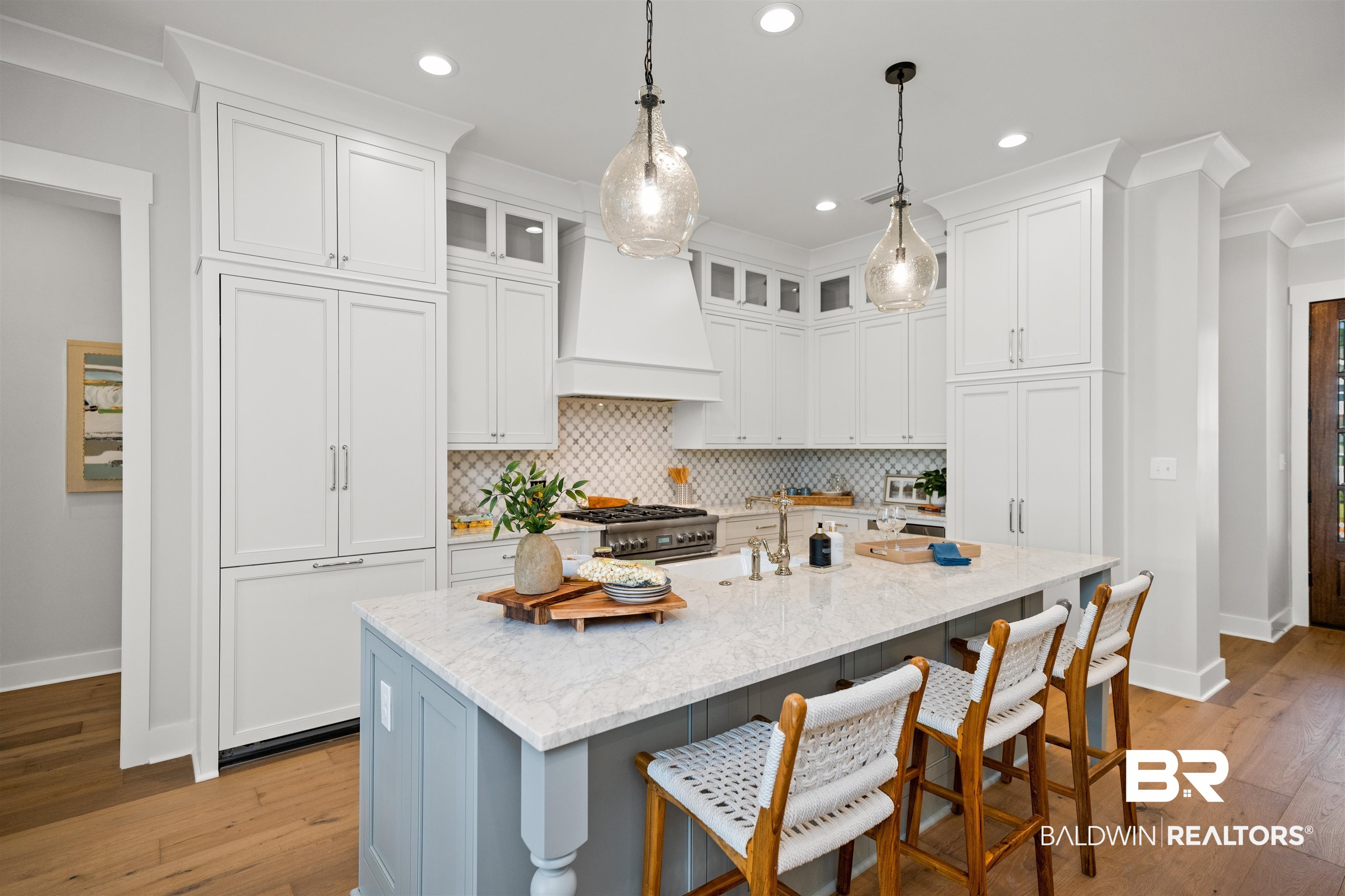 156 Hyacinth Street Fairhope, AL 36532 - Photo 13 of 61 Kitchen featuring ornamental molding, backsplash, a breakfast bar, white cabinets, and light wood-style floors