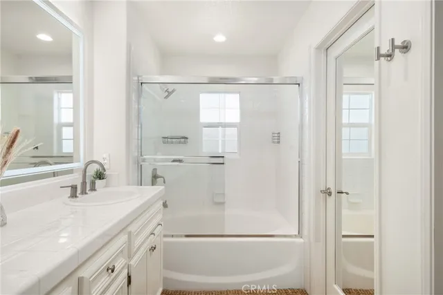 a bathroom with a shower sink vanity and mirror