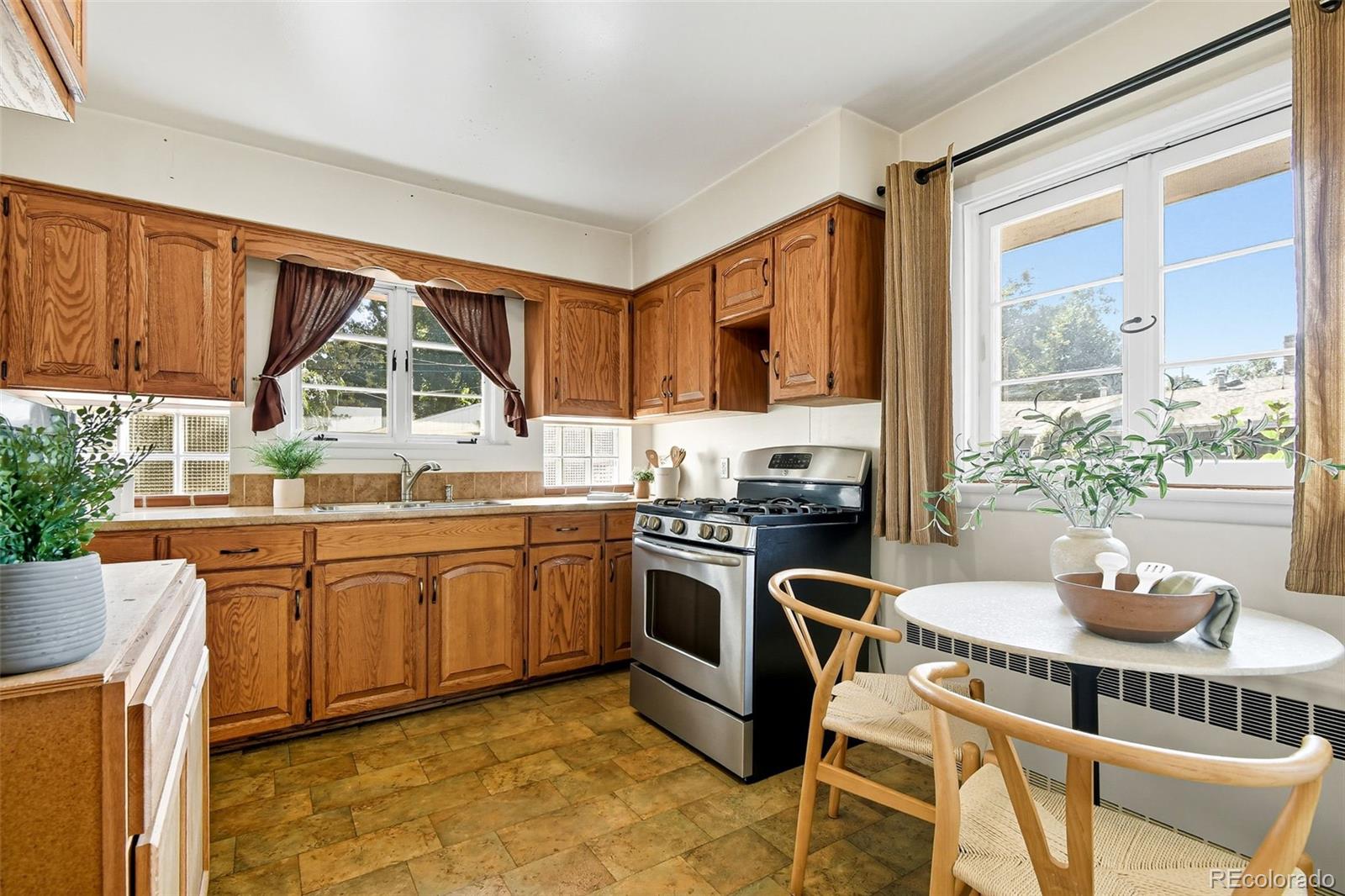 3420 Otis Street Wheat Ridge, CO 80033 - Photo 15 of 32 a kitchen with stainless steel appliances granite countertop a stove a sink dishwasher a dining table and chairs with wooden floor