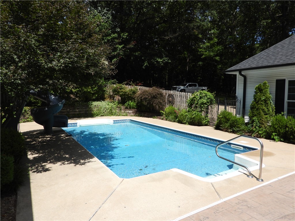19489 Oak Circle Springdale, AR 72764 - Photo 34 of 58 Rectangular swimming pool featuring a concrete surround, integrated steps with a metal handrail, and a blue liner