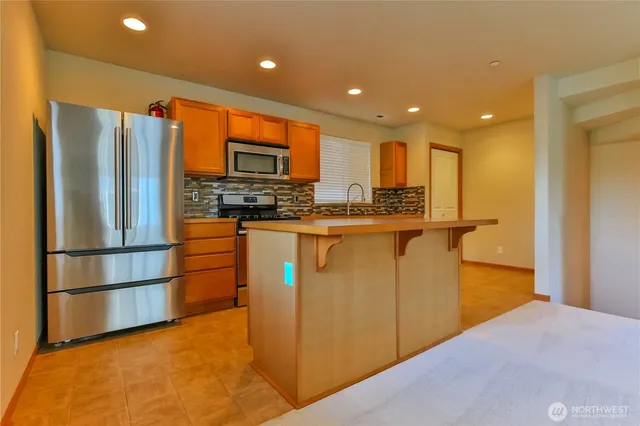 a kitchen with stainless steel appliances granite countertop a refrigerator a stove and a sink