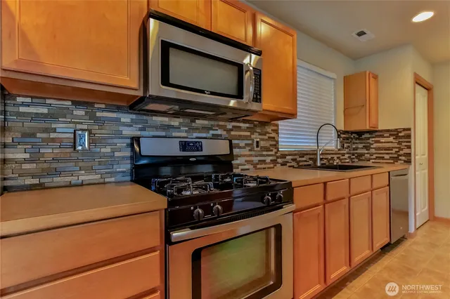 a kitchen with stainless steel appliances a stove microwave and sink