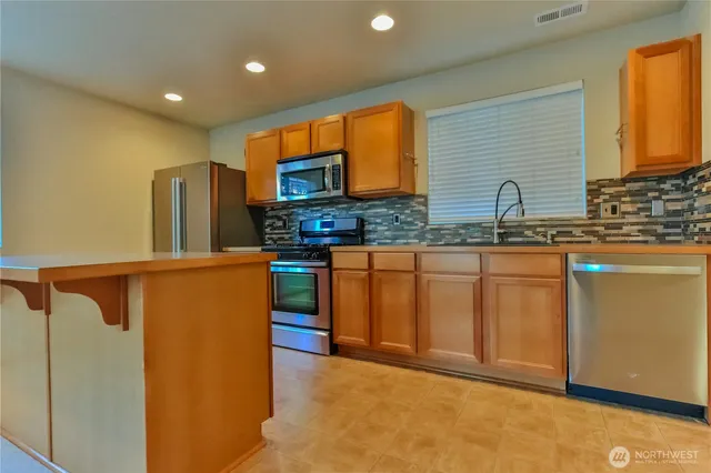 a kitchen with stainless steel appliances granite countertop a sink a stove a refrigerator a washer and dryer