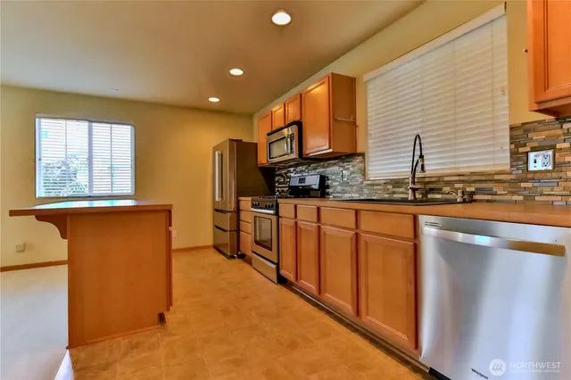 a kitchen with stainless steel appliances granite countertop a sink a stove and a refrigerator