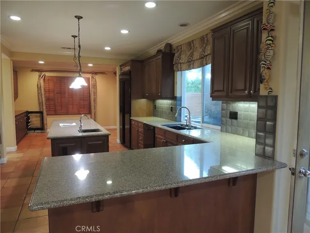 a large kitchen with a large counter top space a sink and stainless steel appliances