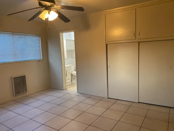 a view of an empty room with window and chandelier fan