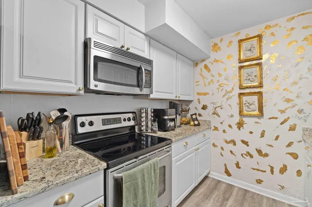 a kitchen with granite countertop white cabinets and stainless steel appliances