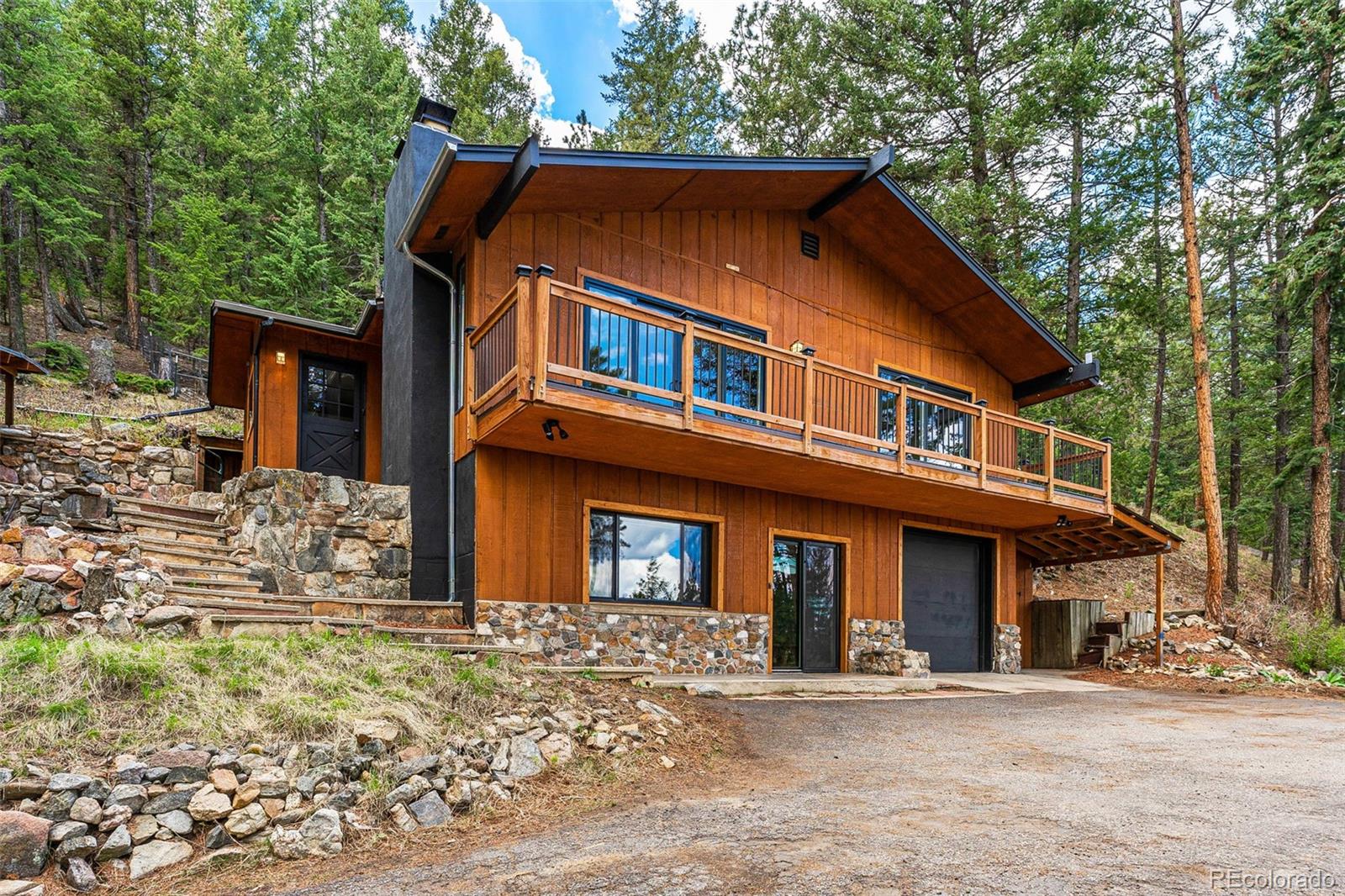 30242 Pine Crest Drive Evergreen, CO 80439 - Photo 2 of 28 a front view of a house with large trees